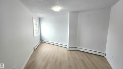 Room featuring neutral white walls, light wood-finish flooring, and white trim - 