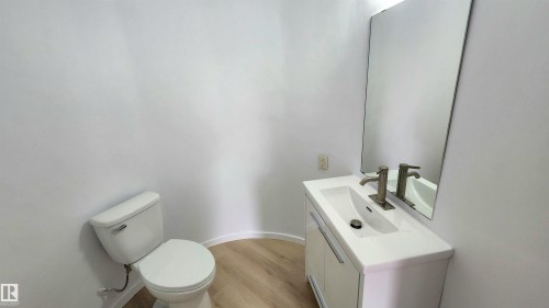 Modern powder room featuring a contemporary white vanity with an integrated sink, brushed nickel faucet, and a frameless rectangular mirror - 9535 147 Avenue, Edmonton, AB - Indoor Photo Showing Bathroom