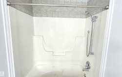 Combination shower and jetted tub unit featuring a built-in seat, a handheld shower fixture, and chrome hardware - 