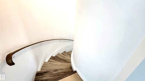 Spiral staircase featuring wood-finish treads, a contrasting dark handrail, and white walls - 9535 147 Avenue, Edmonton, AB - Indoor Photo Showing Other Room