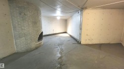 Utility room featuring a curved brick fireplace structure with an arched opening, concrete flooring, and exposed ceiling utilities - 