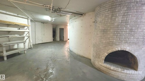 Spacious interior featuring concrete flooring and a curved, white-painted brick alcove - 9535 147 Avenue, Edmonton, AB - Indoor Photo Showing Garage
