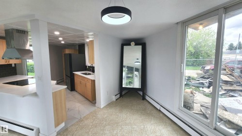 Modern kitchen featuring light wood cabinetry, white countertops, and a dark tile backsplash - 9535 147 Avenue, Edmonton, AB - Indoor