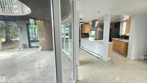 Bright interior space featuring a kitchen with light wood-finish cabinetry, a large kitchen island with a cooktop, and a stainless steel range hood - 9535 147 Avenue, Edmonton, AB -  Photo Showing Other Room