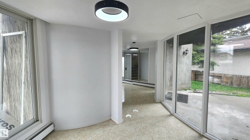 Spacious interior hallway featuring light-toned tile flooring and contemporary circular ceiling lights - 9535 147 Avenue, Edmonton, AB - Indoor Photo Showing Other Room