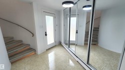 Entryway featuring light-toned tile flooring, a curved staircase with wood-finish treads and a metal handrail, and a frosted glass door - 