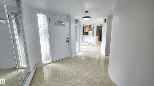 Entryway featuring tile flooring, a white paneled door with an arched window, a frosted sidelight, and a modern ceiling fixture - 9535 147 Avenue, Edmonton, AB - Indoor Photo Showing Other Room