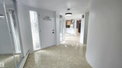 Entryway featuring tile flooring, a white paneled door with an arched window, a frosted sidelight, and a modern ceiling fixture - 