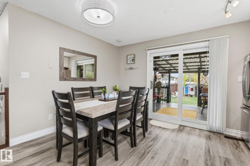 Dining area featuring wood-finish flooring, a contemporary ceiling light fixture, and a sliding glass door providing access to an outdoor covered patio - 15232 120 Nw, Edmonton, AB 