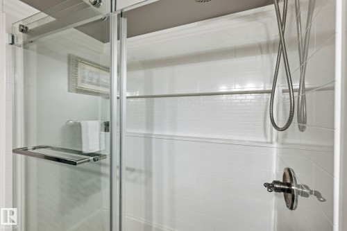 Glass-enclosed shower featuring a handheld showerhead, brushed nickel fixtures, white subway tile accents, and an integrated shower niche - 15232 120 Nw, Edmonton, AB 