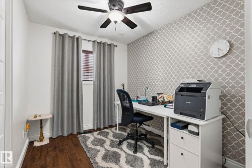 Room featuring wood-finish flooring, a window with horizontal blinds, and a ceiling fan with integrated lighting - 15232 120 Nw, Edmonton, AB 