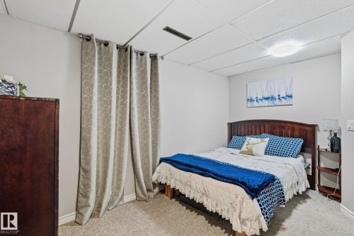 Carpeted room featuring a drop ceiling with recessed lighting - 15232 120 Nw, Edmonton, AB 