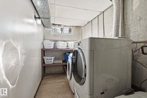 Dedicated laundry area featuring a stacked washer and dryer, a utility sink, and a high window - 15232 120 Nw, Edmonton, AB 
