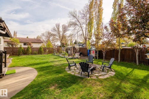 Expansive green lawn with a circular stone fire pit feature - 15232 120 Nw, Edmonton, AB 