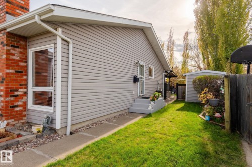 Exterior featuring light gray siding, a brick chimney, and a concrete pathway - 15232 120 Nw, Edmonton, AB 