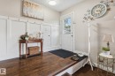 Entryway featuring dark wood-finish flooring, white wainscoting, and a paneled door with glass inserts - 15232 120 Nw, Edmonton, AB 
