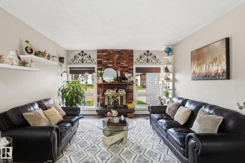 Brick fireplace with a dark mantel, flanked by two windows - 15232 120 Nw, Edmonton, AB 