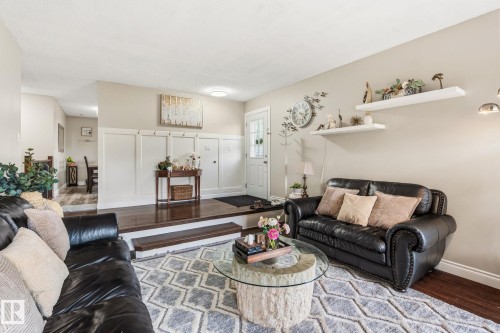 Living area featuring a two-tier layout with wood-finish flooring, a neutral color palette, recessed lighting, white baseboards, and wainscoting details at the entry - 15232 120 Nw, Edmonton, AB 