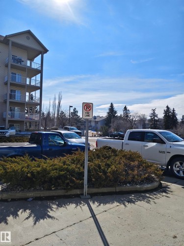 The property features a multi-story building with balconies, set against a clear blue sky - 209 7511 171 Street Nw, Edmonton, AB - Outdoor