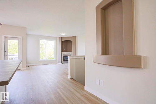 Spacious living area featuring light wood-finish flooring, a contemporary fireplace with a stone surround, and an integrated media niche - 82 Meadowview Point(E), Sherwood Park, AB - Indoor Photo Showing Other Room