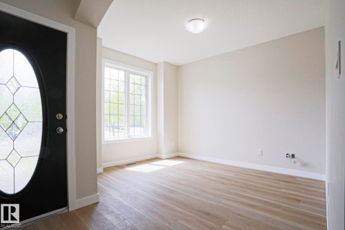 Entryway featuring a black door with leaded glass, wood-finish flooring, white baseboards, and a large window with grid panes - 82 Meadowview Point(E), Sherwood Park, AB - Indoor Photo Showing Other Room