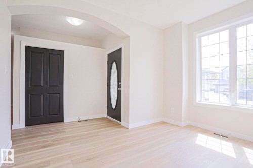 Foyer featuring an arched entryway, light wood-finish flooring, and a window with grid patterns - 82 Meadowview Point(E), Sherwood Park, AB - Indoor Photo Showing Other Room