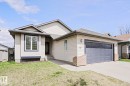 Front exterior featuring light-colored siding, a dark gray garage door, and a concrete driveway - 82 Meadowview Point(E), Sherwood Park, AB  - Outdoor 
