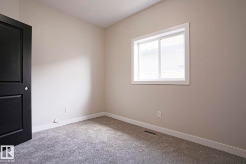 Neutral tone walls with white trim, gray textured carpeting, and a black paneled door with a round silver knob - 82 Meadowview Point(E), Sherwood Park, AB - Indoor Photo Showing Other Room