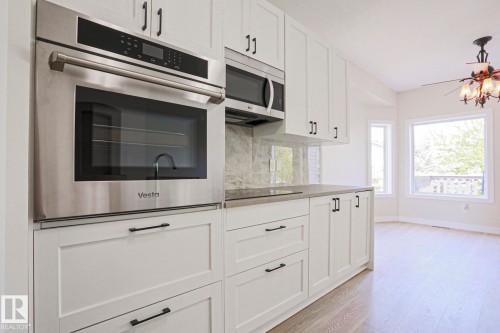 Kitchen featuring stainless steel built-in oven, microwave, white shaker-style cabinetry, and light-toned wood-finish flooring - 82 Meadowview Point(E), Sherwood Park, AB - Indoor Photo Showing Kitchen