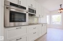 Kitchen featuring stainless steel built-in oven, microwave, white shaker-style cabinetry, and light-toned wood-finish flooring - 82 Meadowview Point(E), Sherwood Park, AB  - Indoor Photo Showing Kitchen 