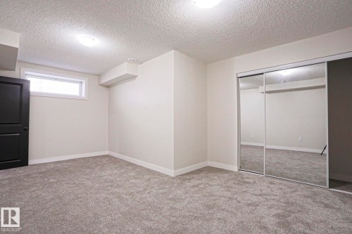 Spacious room with gray carpeting, white walls, a black paneled door, and a mirrored sliding closet door - 82 Meadowview Point(E), Sherwood Park, AB - Indoor
