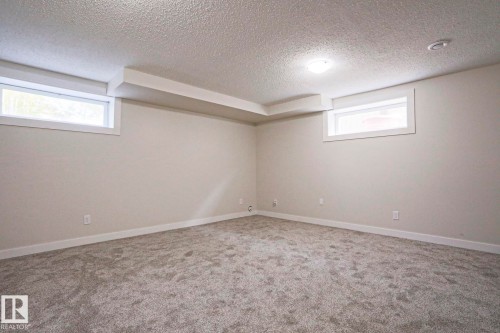 Finished lower-level room featuring light gray carpeting, neutral wall paint, and white trim - 82 Meadowview Point(E), Sherwood Park, AB - Indoor