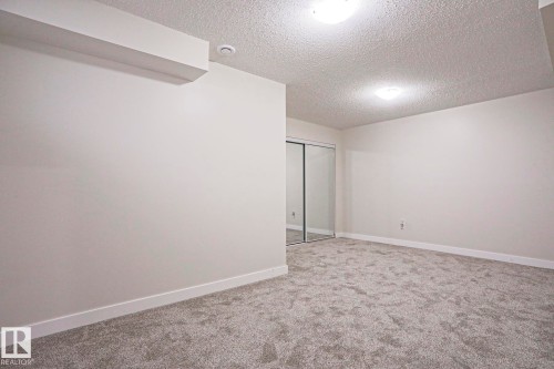 Spacious room featuring gray textured carpeting, white baseboards, and neutral wall tones - 82 Meadowview Point(E), Sherwood Park, AB - Indoor Photo Showing Other Room