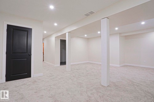 Spacious finished basement featuring light grey carpet, recessed lighting, white trim, and a contrasting dark paneled door - 82 Meadowview Point(E), Sherwood Park, AB - Indoor