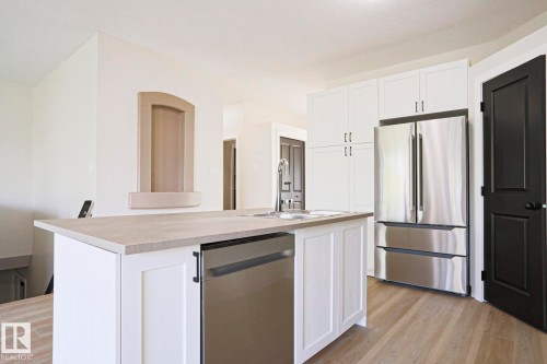 Kitchen featuring a central island with an undermount sink, stainless steel dishwasher, and light-toned countertop - 82 Meadowview Point(E), Sherwood Park, AB - Indoor Photo Showing Kitchen