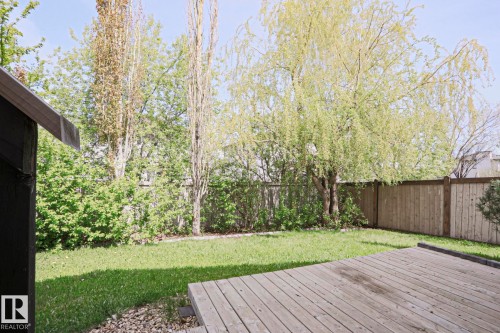 Expansive backyard featuring a natural wood deck, manicured lawn, mature trees, and a privacy fence - 82 Meadowview Point(E), Sherwood Park, AB - Outdoor