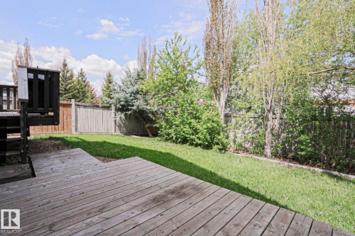 Expansive wooden deck with stairs leading to a spacious, fenced yard featuring mature trees and a manicured lawn - 82 Meadowview Point(E), Sherwood Park, AB - Outdoor