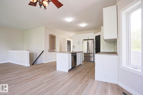 Open-concept kitchen featuring white cabinetry, stainless steel appliances, and an island with a sink - 82 Meadowview Point(E), Sherwood Park, AB - Indoor Photo Showing Kitchen