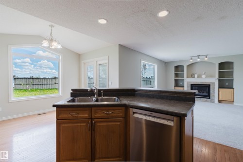 Kitchen island featuring a dual-basin sink, stainless steel dishwasher, and wood-finish cabinetry - 3534 Mclean Crescent, Edmonton, AB - Indoor Photo Showing Kitchen With Double Sink
