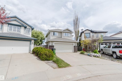 Front exterior showcasing a two-story residence with light-toned siding, an attached garage, and a concrete driveway - 3534 Mclean Crescent, Edmonton, AB - Outdoor With Facade