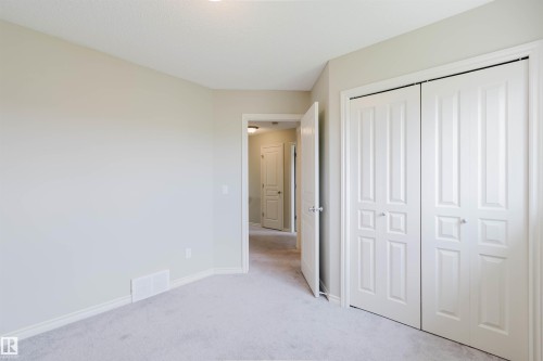 Carpeted room featuring neutral wall tones, white baseboards, and bi-fold closet doors - 3534 Mclean Crescent, Edmonton, AB - Indoor
