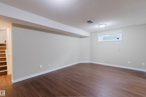 Finished lower level space featuring wood-finish flooring, light neutral wall tones, and white trim - 3534 Mclean Crescent, Edmonton, AB - Indoor Photo Showing Other Room