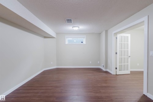 Spacious room featuring wood-finish flooring, light neutral wall paint, and white trim - 3534 Mclean Crescent, Edmonton, AB - Indoor Photo Showing Other Room