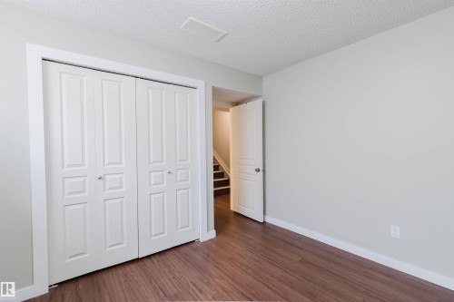 Room featuring wood-finish flooring, light grey painted walls, white baseboards, and a bi-fold closet with paneled doors - 3534 Mclean Crescent, Edmonton, AB - Indoor