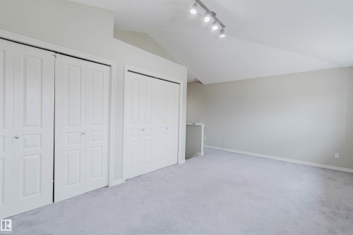 Spacious room featuring multiple bi-fold closet doors, track lighting, an angled ceiling, and wall-to-wall carpeting - 3534 Mclean Crescent, Edmonton, AB - Indoor Photo Showing Other Room