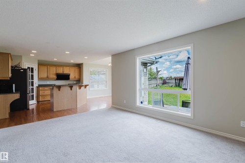 Open-concept living area featuring light carpeting and a large picture window - 3534 Mclean Crescent, Edmonton, AB - Indoor