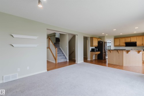 Open-concept living space featuring light gray carpeting, a kitchen with wood cabinetry, and recessed lighting - 3534 Mclean Crescent, Edmonton, AB - Indoor Photo Showing Kitchen