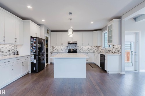 Spacious kitchen featuring white cabinetry, a center island with countertop, and wood-finish flooring - 3571 Keswick Boulevard, Edmonton, AB - Indoor Photo Showing Kitchen With Upgraded Kitchen