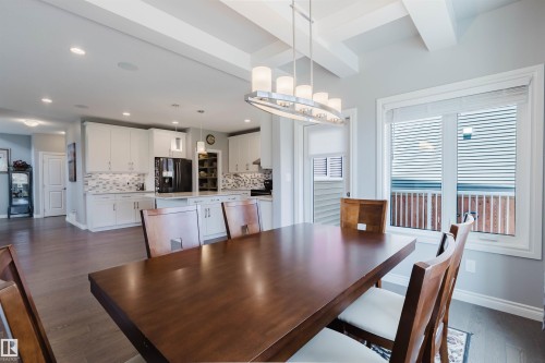 Dining area featuring a coffered ceiling, a contemporary linear chandelier, and wood-finish flooring - 3571 Keswick Boulevard, Edmonton, AB - Indoor Photo Showing Dining Room