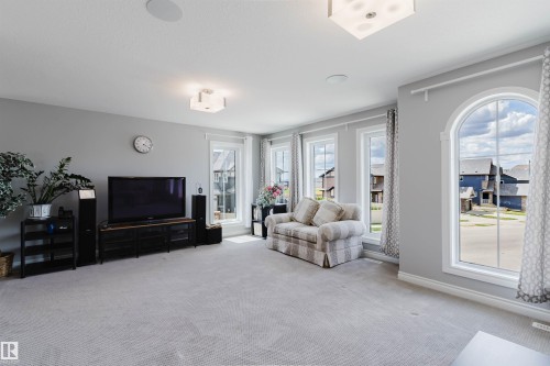 Spacious room featuring light gray walls, plush carpeting, multiple windows including one arched window, and recessed ceiling lighting - 3571 Keswick Boulevard, Edmonton, AB - Indoor Photo Showing Living Room